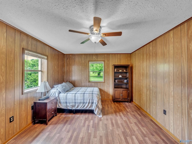 17441 E Limestone Rd, Athens, AL 35613 - bedroom with light wood-style flooring, wood walls, baseboards, a textured ceiling, and ceiling fan