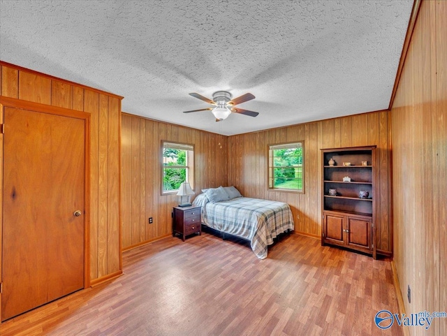 17441 E Limestone Rd, Athens, AL 35613 - bedroom featuring light wood-style flooring, wooden walls, a textured ceiling, a ceiling fan, and baseboards