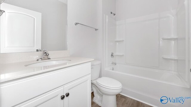 full bathroom featuring toilet, vanity,  shower combination, and hardwood / wood-style flooring