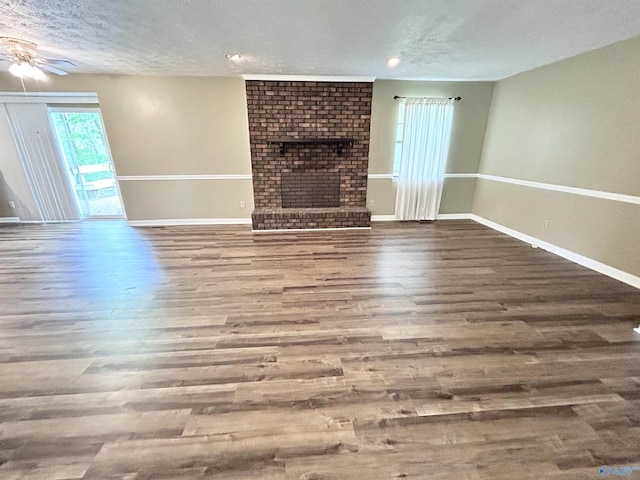 1313 Barry Rd, Anniston, AL 36206 - unfurnished living room with wood finished floors, ceiling fan, a fireplace, baseboards, and a textured ceiling