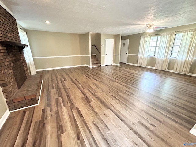 1313 Barry Rd, Anniston, AL 36206 - unfurnished living room with a fireplace, ceiling fan, stairs, baseboards, and wood finished floors