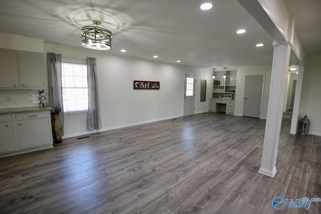 unfurnished living room with hardwood / wood-style flooring, a chandelier, and a wealth of natural light