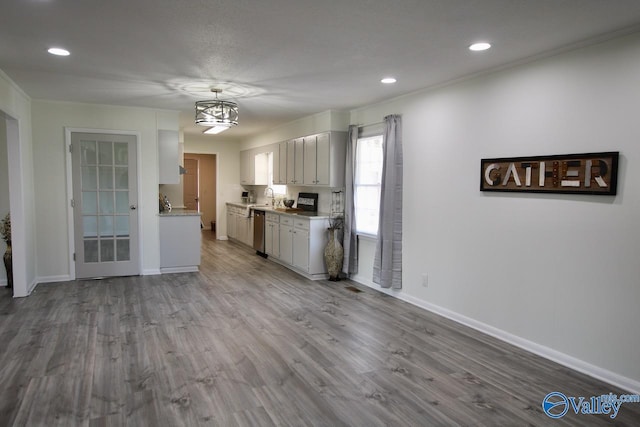 kitchen featuring sink, white cabinetry, ornamental molding, dishwasher, and light hardwood / wood-style floors