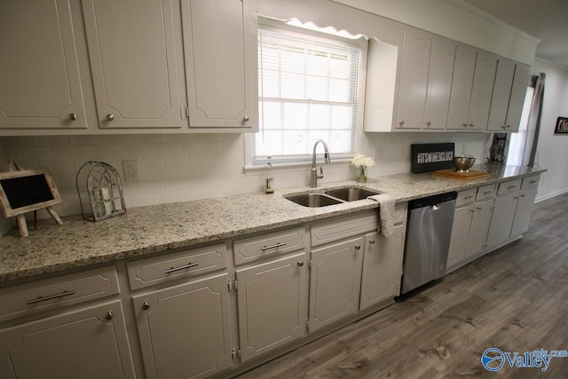 kitchen with sink, dishwasher, light stone countertops, dark hardwood / wood-style flooring, and decorative backsplash