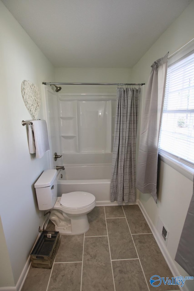 bathroom featuring tile patterned flooring, shower / bath combination with curtain, and toilet