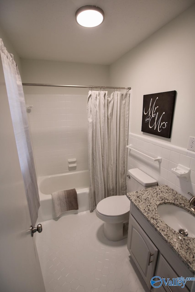 full bathroom with shower / tub combo with curtain, tile walls, tile patterned flooring, vanity, and toilet