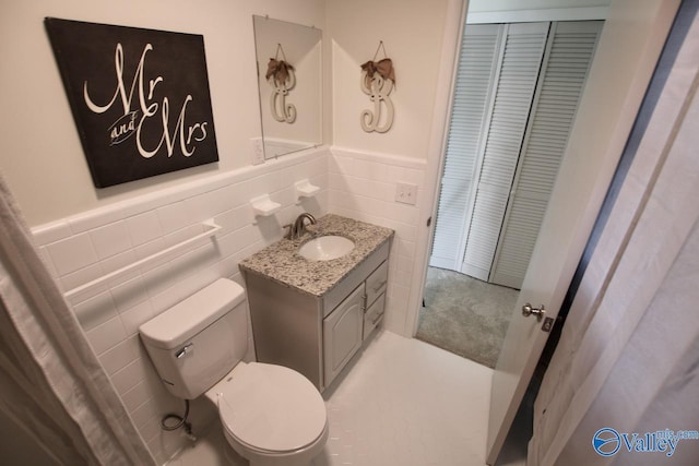 bathroom featuring vanity, tile walls, and toilet