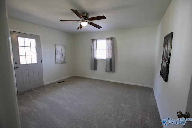 empty room featuring ceiling fan and dark carpet