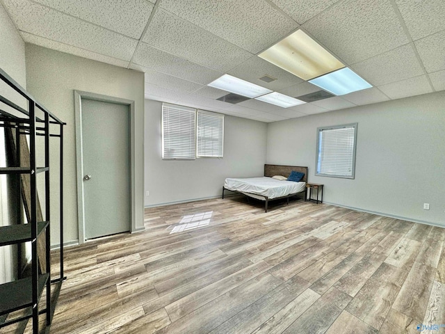 unfurnished bedroom with a paneled ceiling and light wood-type flooring