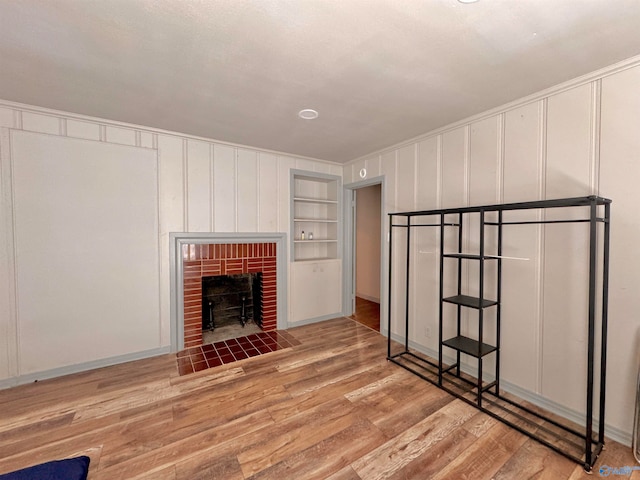 unfurnished living room with hardwood / wood-style flooring, built in features, and a fireplace