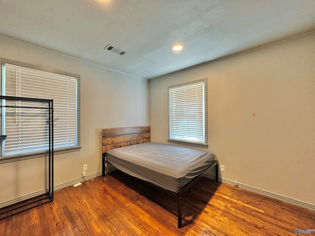 bedroom with multiple windows and hardwood / wood-style floors