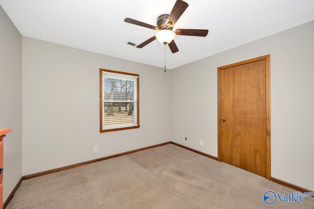 spare room featuring ceiling fan, light carpet, and a textured ceiling