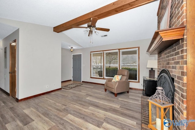 unfurnished room featuring lofted ceiling with beams, ceiling fan, a fireplace, and light hardwood / wood-style floors