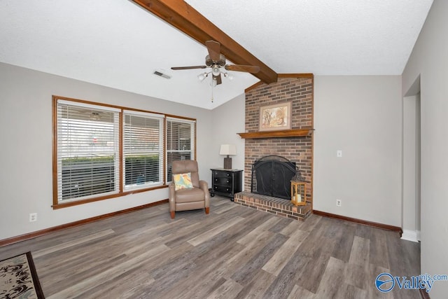 unfurnished living room featuring vaulted ceiling with beams, wood-type flooring, a textured ceiling, ceiling fan, and a fireplace