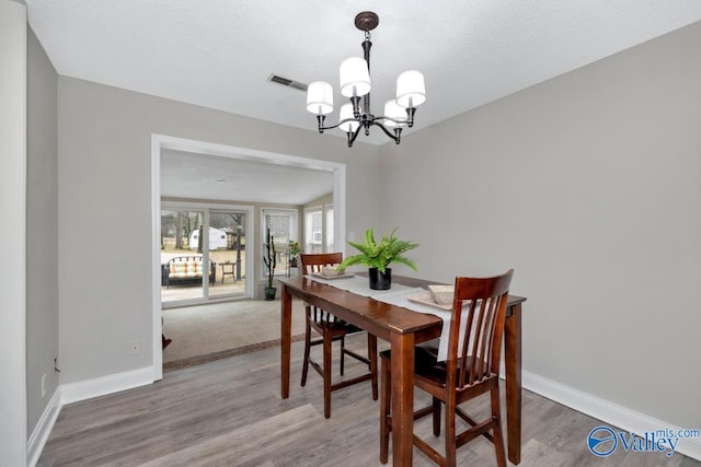 dining space featuring an inviting chandelier, hardwood / wood-style floors, and a textured ceiling