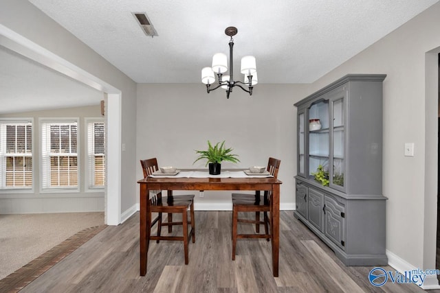 dining area featuring an inviting chandelier, light hardwood / wood-style flooring, and a textured ceiling