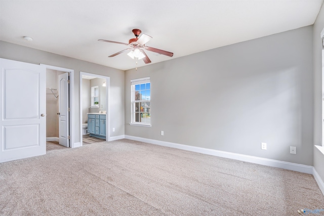 unfurnished bedroom with ensuite bath, ceiling fan, a spacious closet, light colored carpet, and a closet