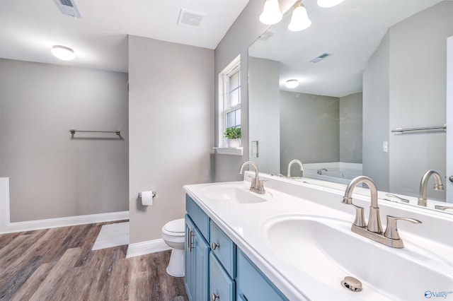 bathroom with hardwood / wood-style floors, a washtub, vanity, and toilet