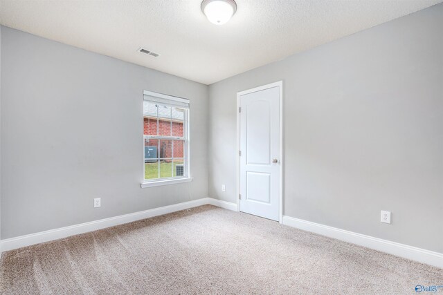 carpeted empty room with a textured ceiling