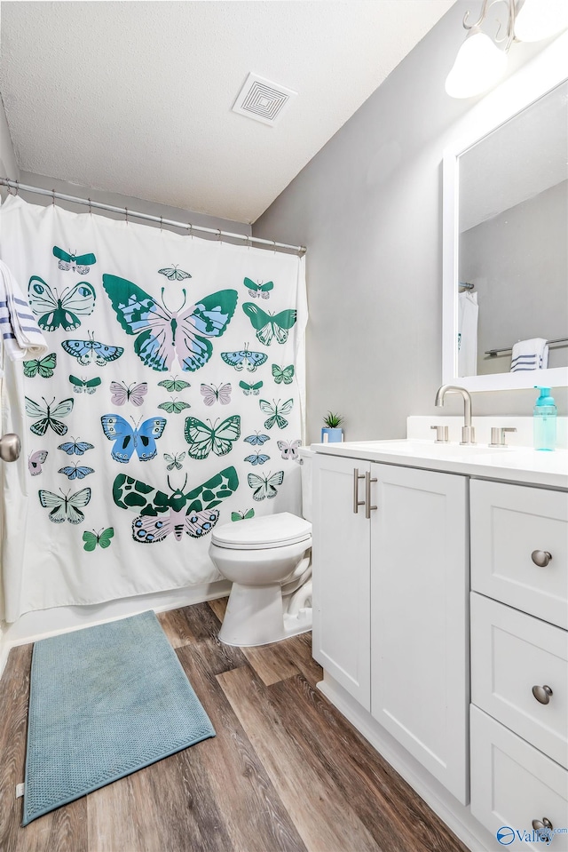 bathroom featuring hardwood / wood-style floors, vanity, a textured ceiling, and toilet