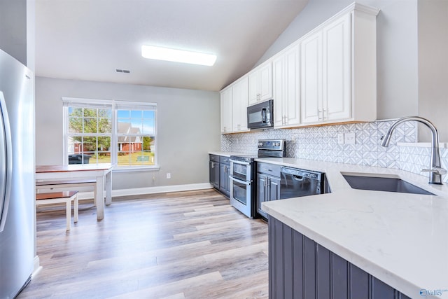 kitchen with black appliances, light stone counters, white cabinetry, light wood-type flooring, and sink