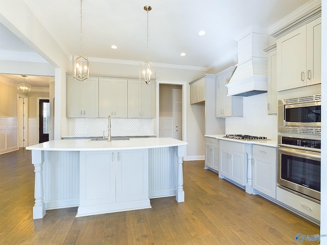 kitchen featuring pendant lighting, stainless steel appliances, an island with sink, and dark wood-type flooring