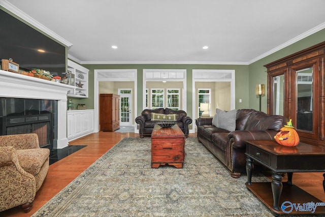 living room featuring ornamental molding, a tiled fireplace, and hardwood / wood-style floors