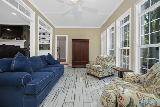 living room with light wood-type flooring, crown molding, ceiling fan, and built in features