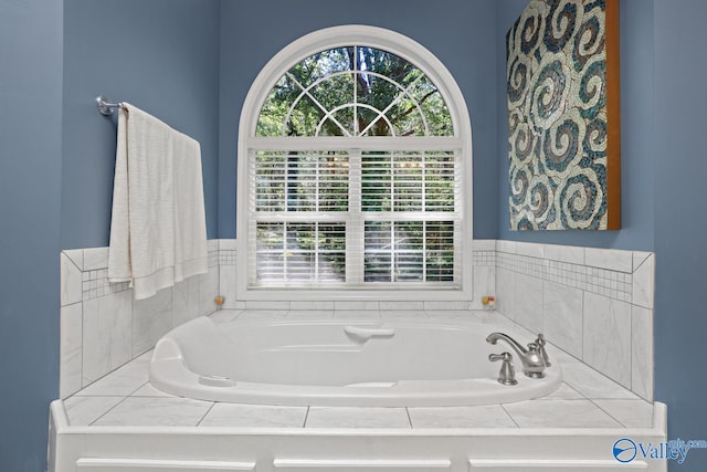 bathroom featuring tiled bath and a wealth of natural light