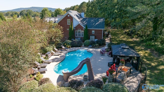 view of pool with a patio, a water slide, a gazebo, and a mountain view