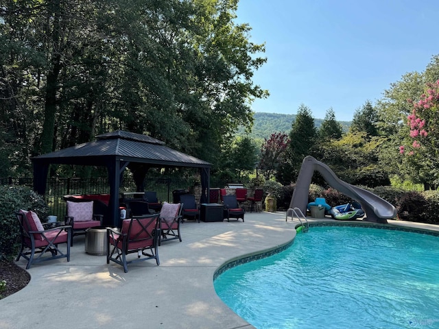 view of pool featuring a patio, outdoor lounge area, a gazebo, and a water slide