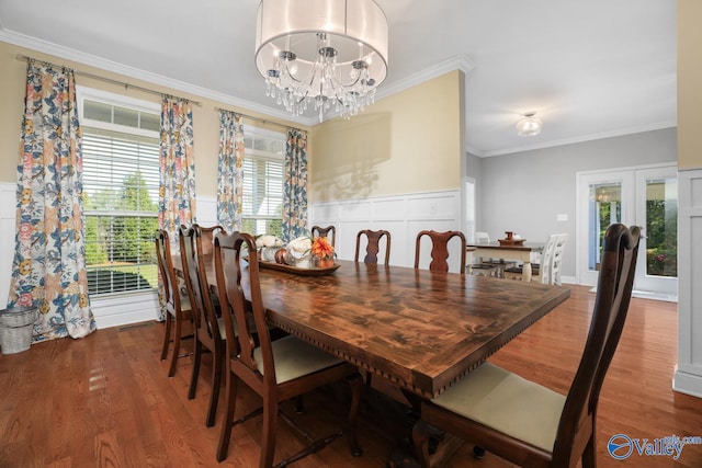 dining space with french doors, hardwood / wood-style floors, crown molding, and a notable chandelier