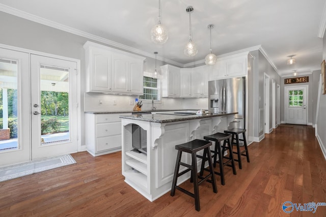 kitchen featuring white cabinets, dark stone countertops, a kitchen island, and stainless steel refrigerator with ice dispenser