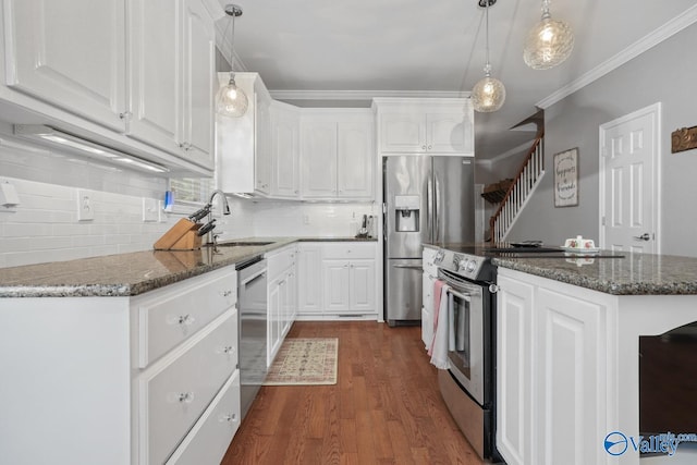 kitchen featuring white cabinetry, hanging light fixtures, stainless steel appliances, dark stone countertops, and crown molding