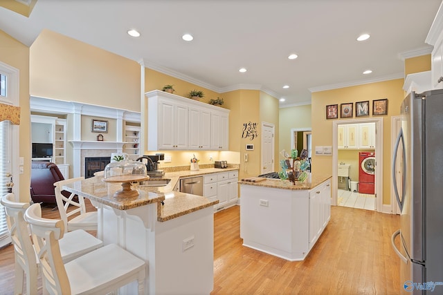 kitchen featuring white cabinets, a kitchen island, light stone counters, freestanding refrigerator, and light wood-type flooring