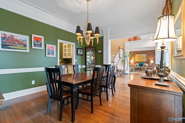 dining space featuring an inviting chandelier, baseboards, ornamental molding, and wood finished floors