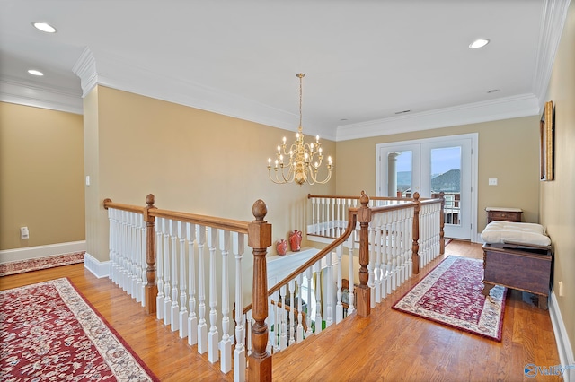 hall with ornamental molding, baseboards, an upstairs landing, and wood finished floors