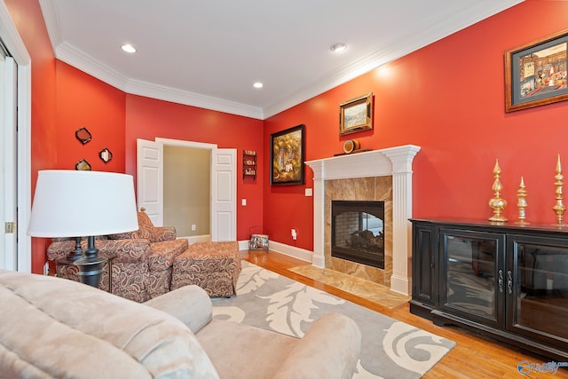 living area with baseboards, wood finished floors, crown molding, a fireplace, and recessed lighting