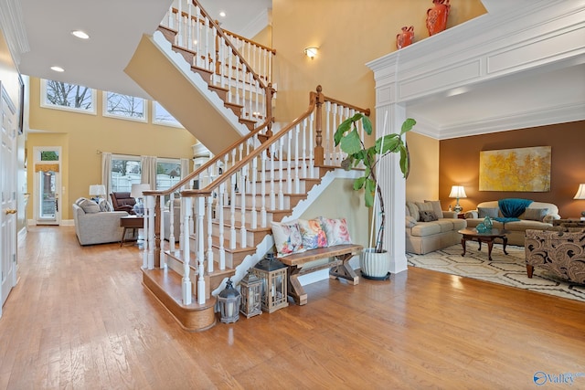 staircase featuring ornamental molding, recessed lighting, a high ceiling, and wood finished floors