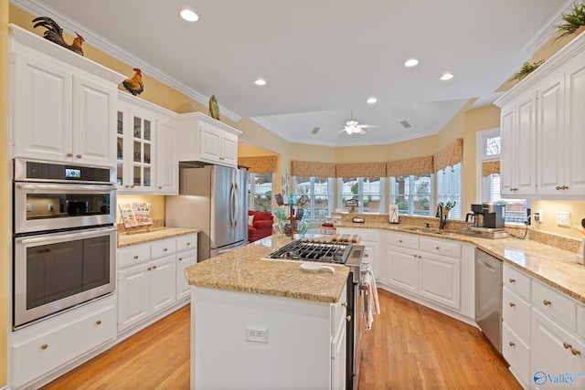 kitchen featuring appliances with stainless steel finishes, light wood-type flooring, a sink, and crown molding