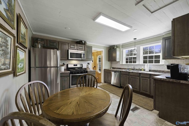 kitchen featuring crown molding, stainless steel appliances, tasteful backsplash, visible vents, and a sink