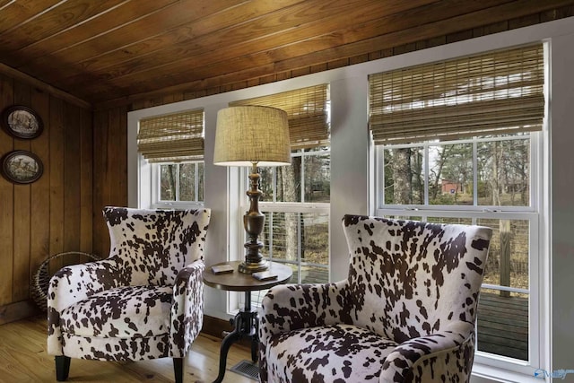 living area with wooden ceiling, wood finished floors, and wooden walls