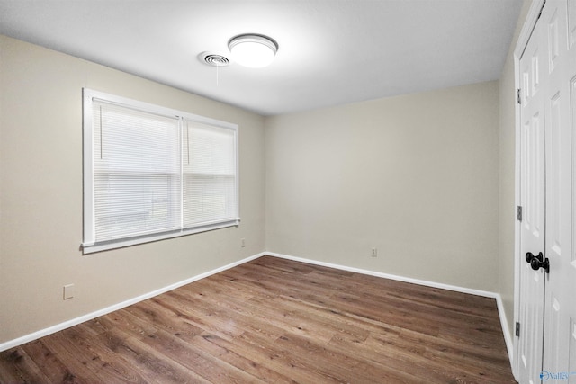 spare room featuring wood finished floors, baseboards, and visible vents