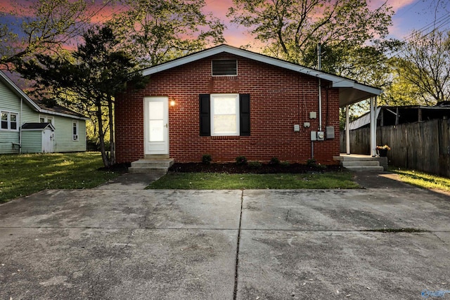 view of front facade with brick siding, fence, and a front lawn