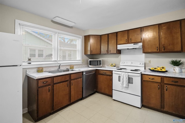 kitchen featuring a sink, light countertops, appliances with stainless steel finishes, under cabinet range hood, and brown cabinets