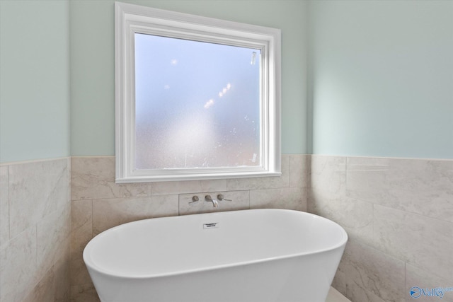 bathroom featuring a bath and tile walls