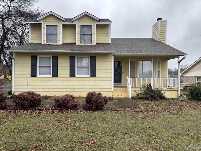 view of front facade with covered porch, a shingled roof, a chimney, and a front yard