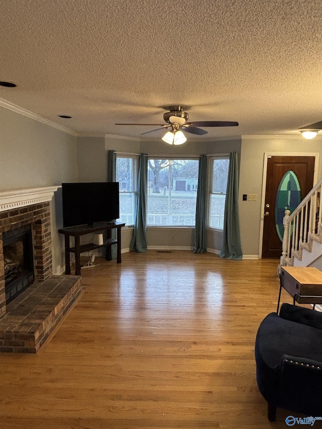 living room with a brick fireplace, ornamental molding, and wood finished floors