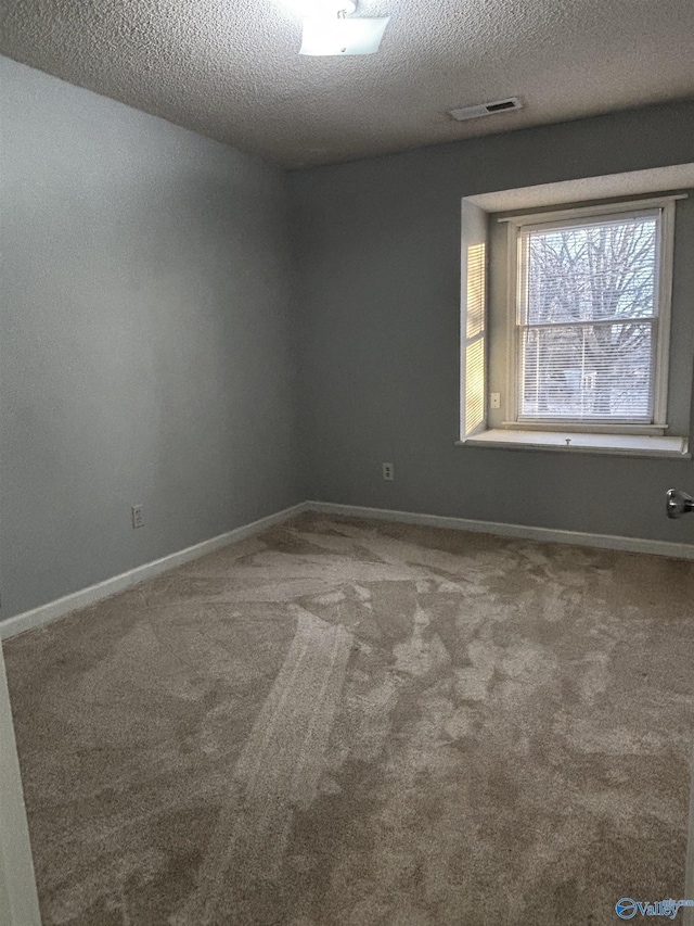 carpeted empty room featuring a textured ceiling, visible vents, and baseboards