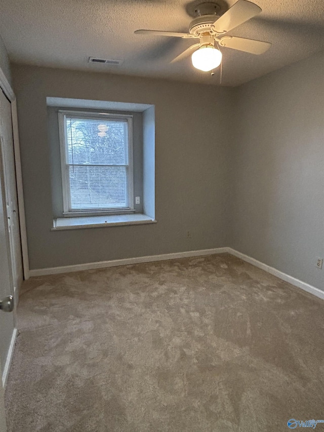 unfurnished bedroom with baseboards, visible vents, ceiling fan, a textured ceiling, and carpet floors